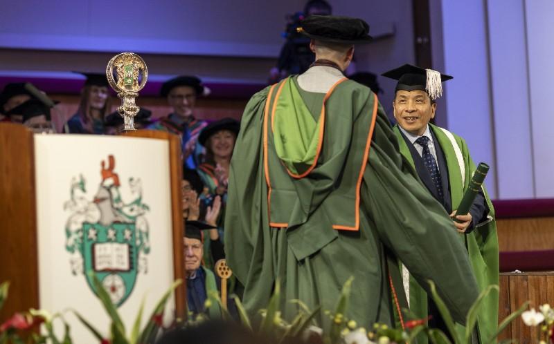A PhD graduate receives a certificate from the Vice Chancellor at a graduation ceremony at the University of Leeds