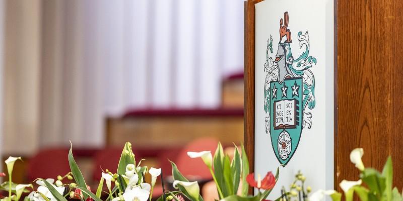 University of Leeds crest on a podium at graduation with flowers in foreground